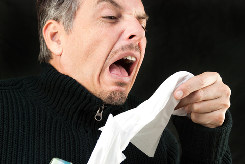 Man Sneezing into Tissue